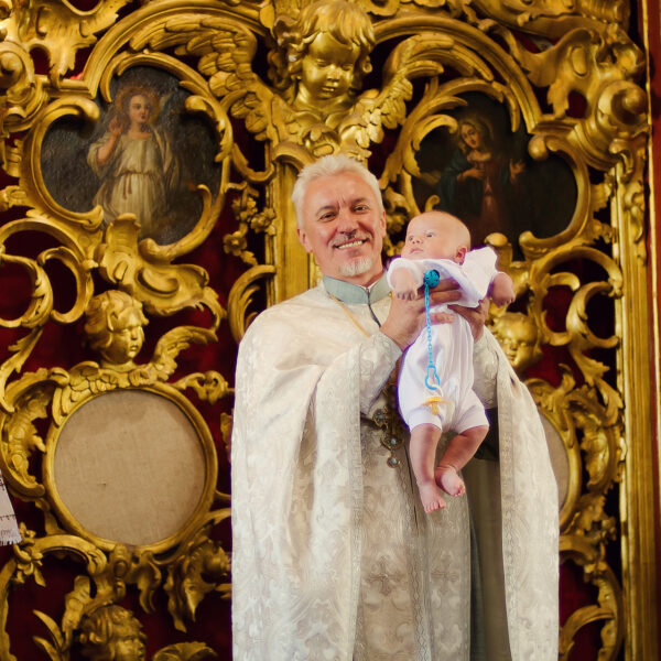 Ksiądz składa gratulacje dziecku i rodzicom z okazji chrztu. Rodzina przy ołtarzu w czasie chrztu — fotograf Lublin studiyasveta