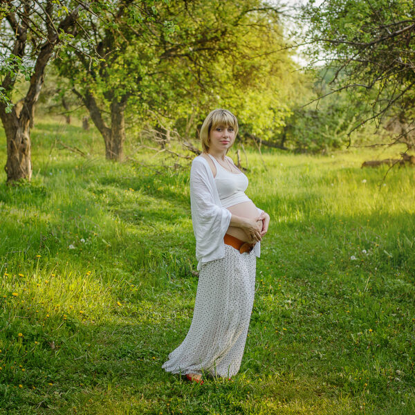 Kobieta w ciąży w sukni wśród natury