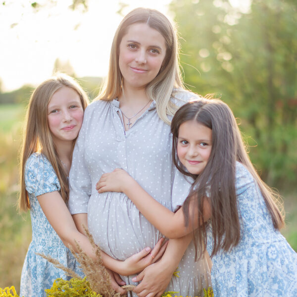 Mama w ciąży z dziećmi w ramionach