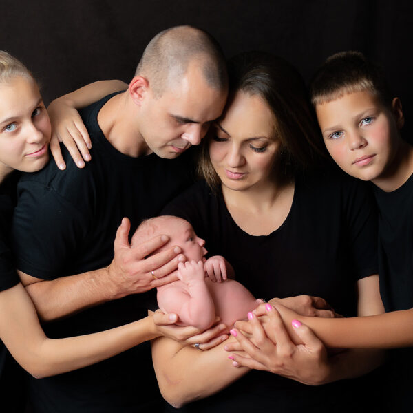 Rodzinne zdjęcie z noworodkiem w ramionach rodziny