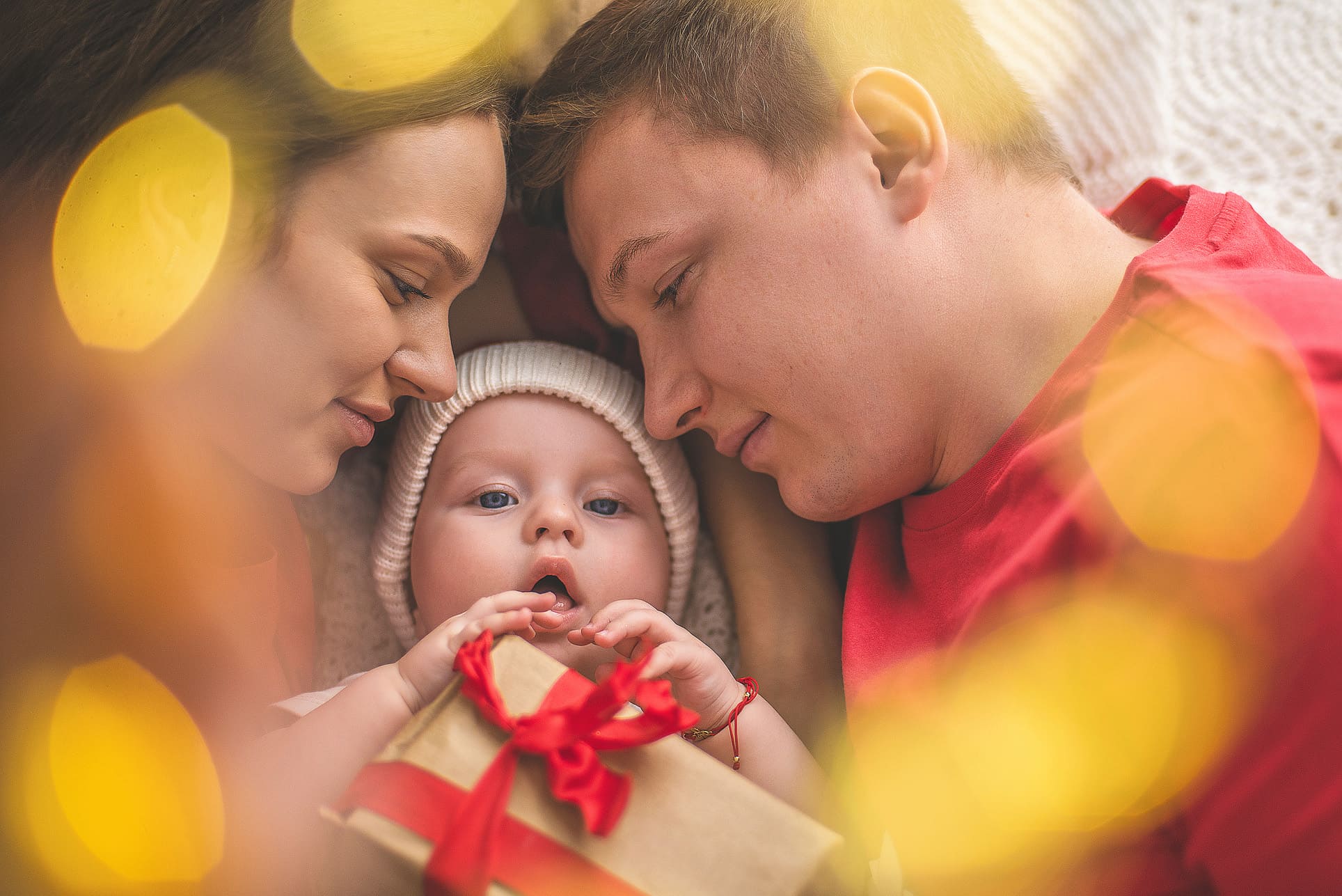 Rodzinna sesja zdjęciowa w świątecznym klimacie Bożego Narodzenia tata mama dziecko prezent świąteczny
