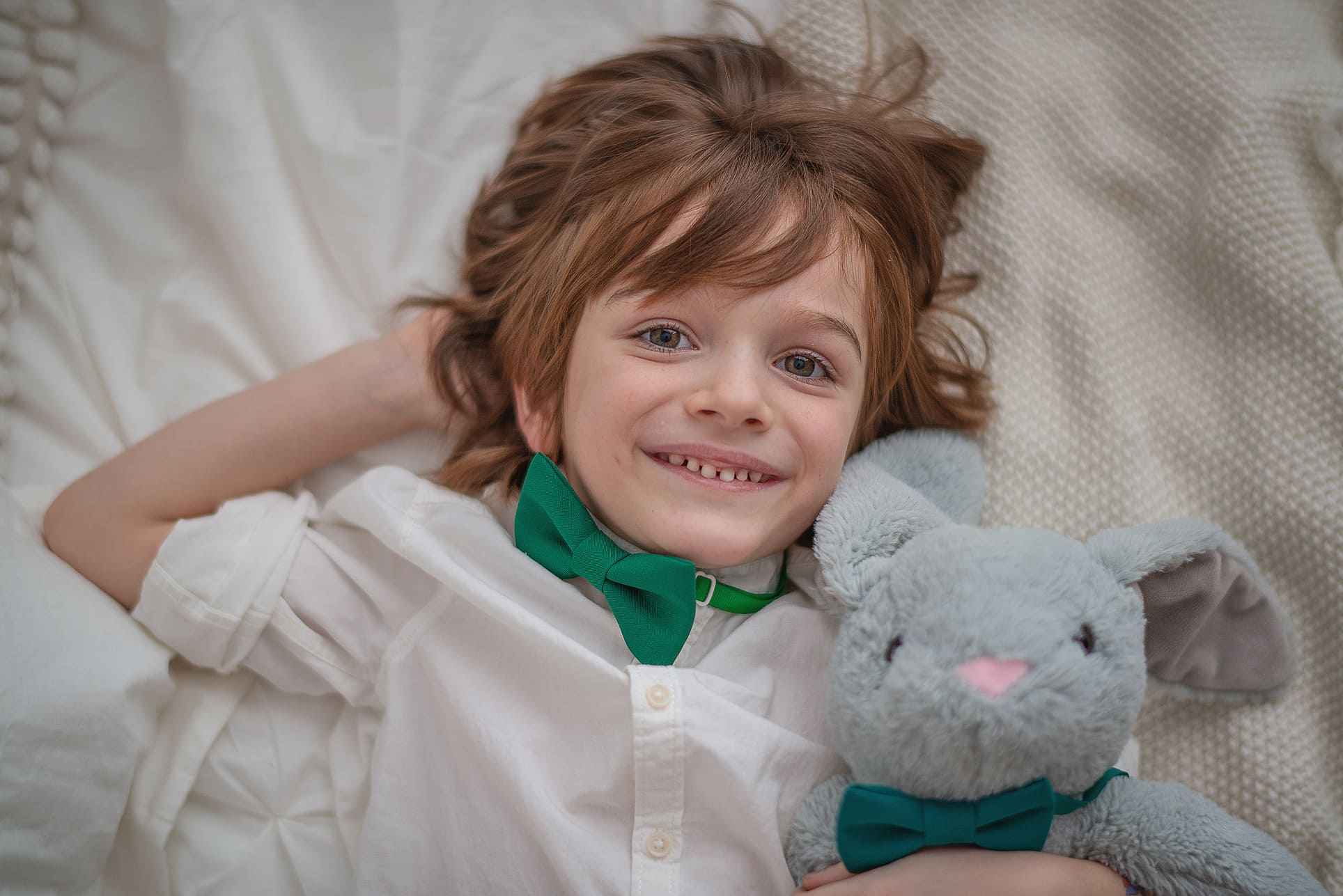 Wiosenna sesja zdjęciowa z dzieckiem na tle dekoracji Wielkanocnych w studiu chłopiec śmiejący się z królikiem
